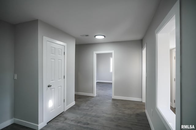 hall featuring dark wood-style floors, visible vents, and baseboards