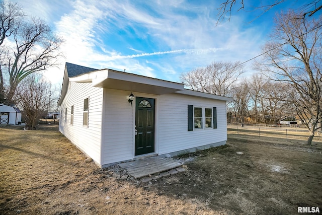 back of property featuring fence and a lawn