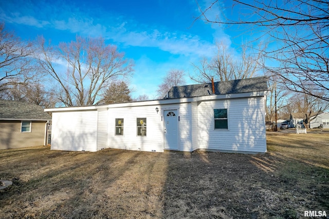 rear view of house with a shingled roof and a lawn