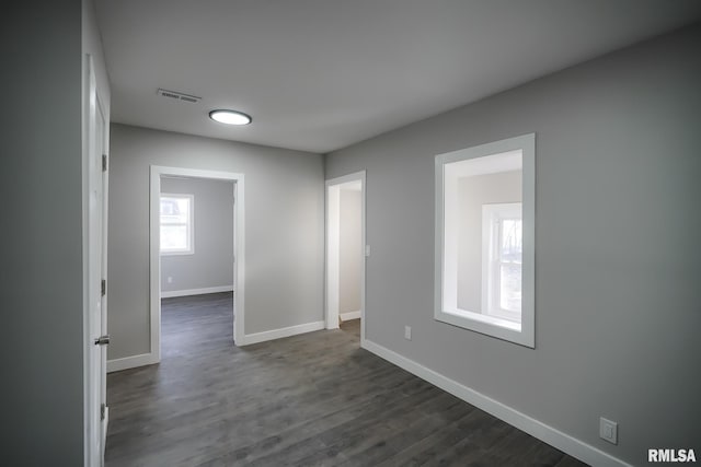 unfurnished room featuring dark wood-style floors, baseboards, and visible vents