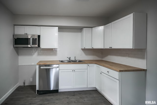 kitchen with dark wood finished floors, decorative backsplash, butcher block countertops, appliances with stainless steel finishes, and a sink