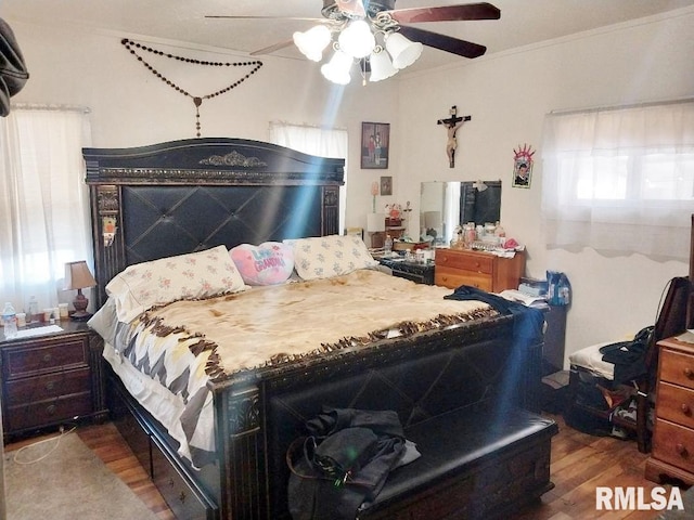 bedroom featuring a ceiling fan, ornamental molding, and wood finished floors