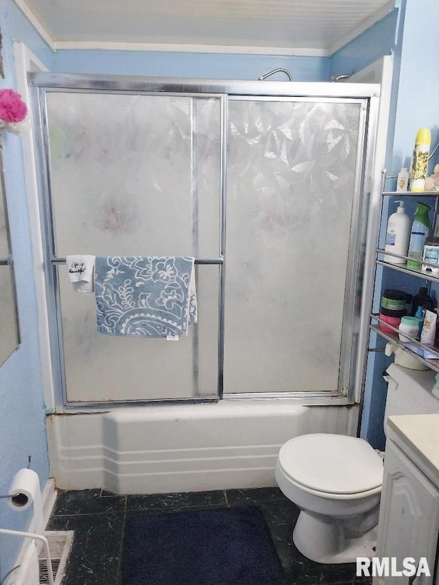 bathroom featuring toilet, bath / shower combo with glass door, and vanity