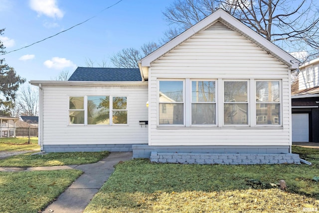 exterior space featuring a front lawn and roof with shingles