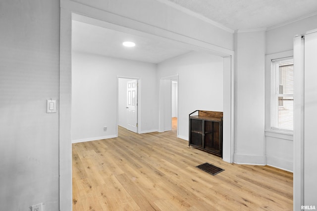 spare room with visible vents, crown molding, baseboards, and wood finished floors