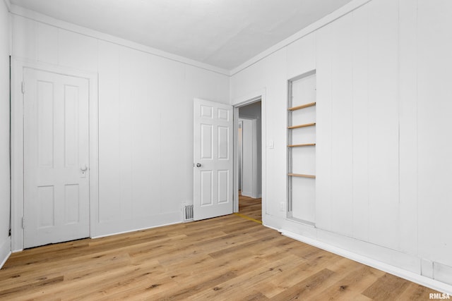 unfurnished bedroom featuring visible vents, crown molding, and light wood-style flooring