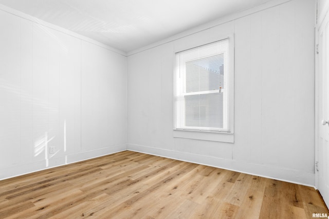 unfurnished room with plenty of natural light, light wood-style flooring, and a decorative wall