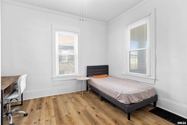 bedroom with light wood-style floors, baseboards, and crown molding