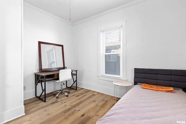 bedroom with ornamental molding, light wood-style flooring, and baseboards