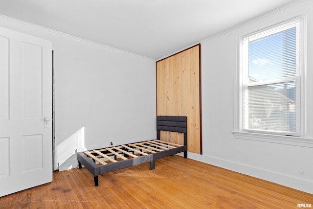 interior space with ornamental molding, wood-type flooring, and baseboards