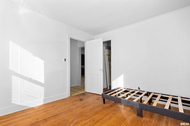 interior space featuring ornamental molding, wood-type flooring, and baseboards