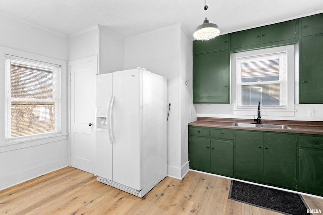 kitchen with white fridge with ice dispenser, a sink, light wood-style flooring, and green cabinetry