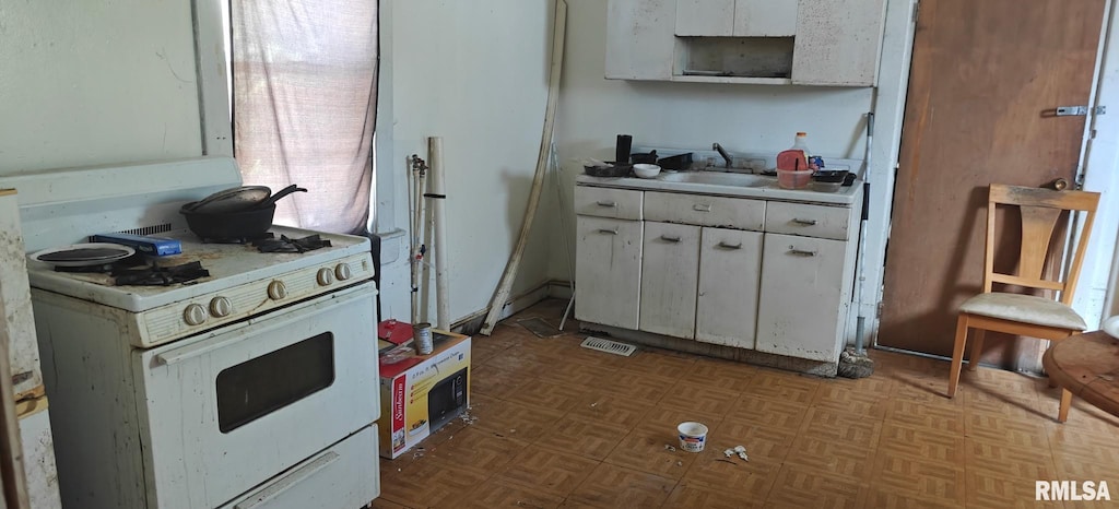 kitchen featuring light countertops, visible vents, white cabinetry, a sink, and white range with gas stovetop