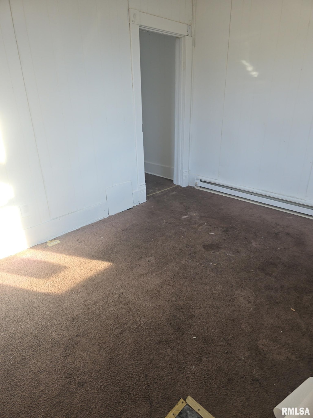 spare room with carpet and a baseboard heating unit