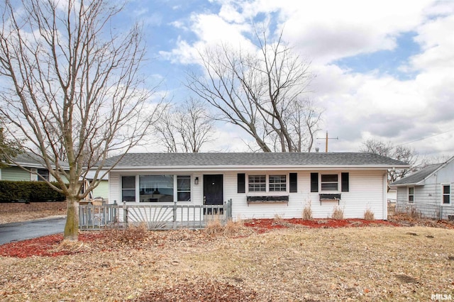 single story home with fence, a porch, and roof with shingles