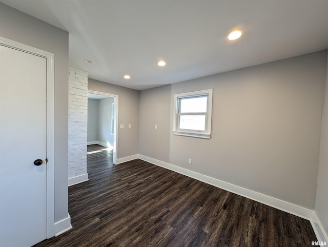 spare room with dark wood-type flooring, recessed lighting, and baseboards