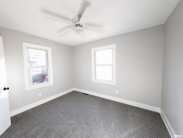 empty room with baseboards, dark colored carpet, and a wealth of natural light