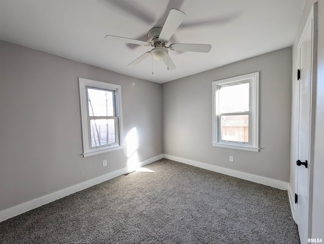 spare room with carpet floors, baseboards, and a wealth of natural light