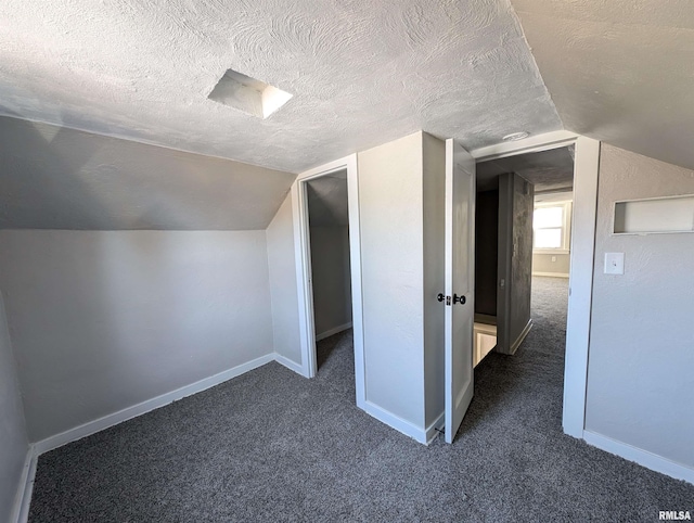 bonus room featuring a textured ceiling, dark colored carpet, and baseboards