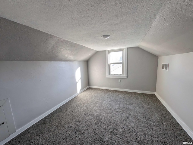 additional living space featuring a textured ceiling, carpet flooring, visible vents, baseboards, and vaulted ceiling