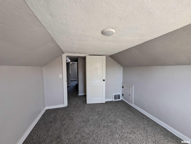 bonus room featuring vaulted ceiling, dark colored carpet, visible vents, and baseboards