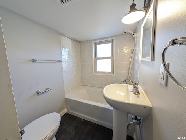 bathroom with shower / bathing tub combination, wood finished floors, and toilet