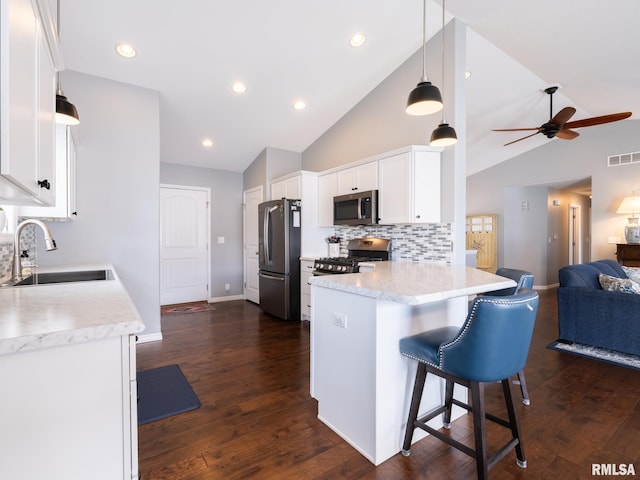 kitchen with visible vents, appliances with stainless steel finishes, open floor plan, white cabinetry, and a sink