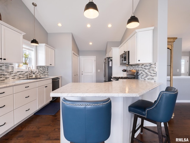 kitchen with stainless steel appliances, vaulted ceiling, white cabinets, and a sink