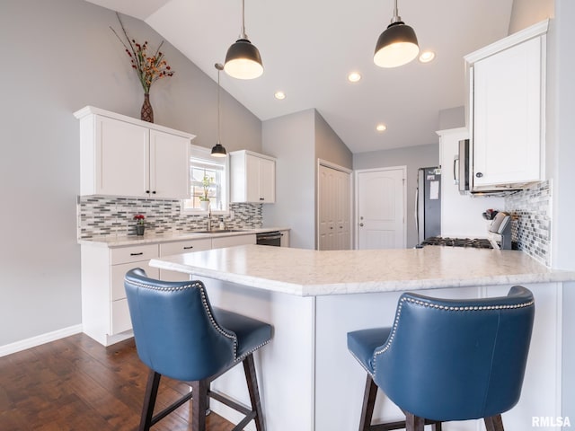 kitchen featuring vaulted ceiling, stainless steel appliances, a sink, and white cabinetry