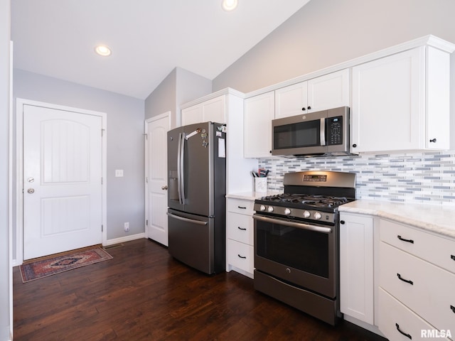 kitchen featuring dark wood-style flooring, stainless steel appliances, tasteful backsplash, white cabinetry, and vaulted ceiling