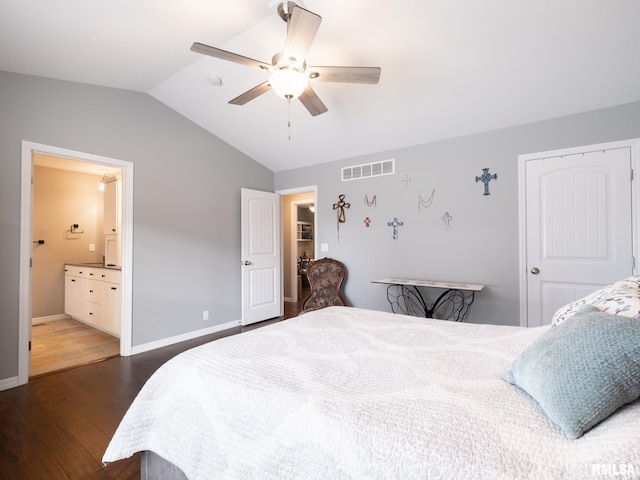 bedroom with lofted ceiling, connected bathroom, dark wood-type flooring, visible vents, and baseboards