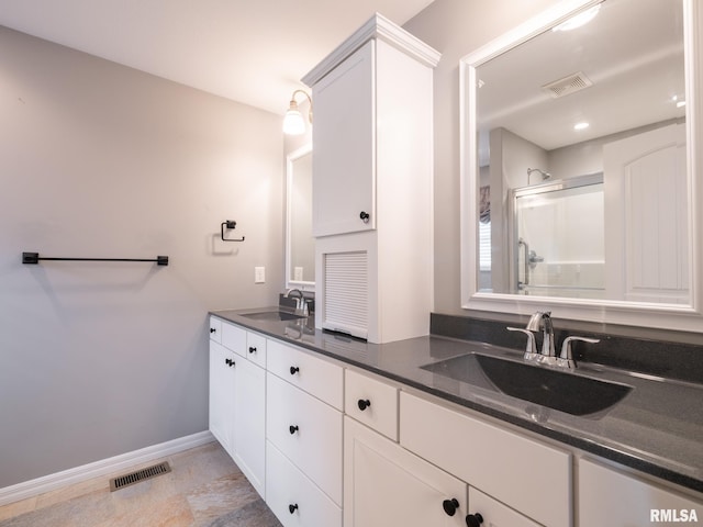 bathroom with a stall shower, visible vents, and a sink