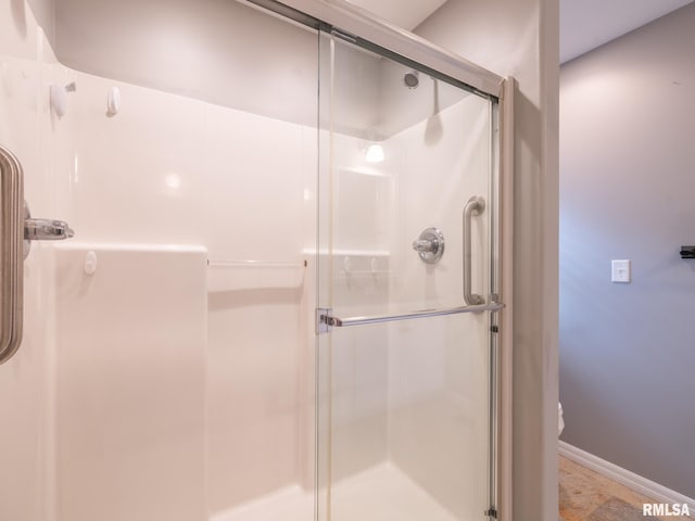 bathroom with a stall shower, toilet, and baseboards