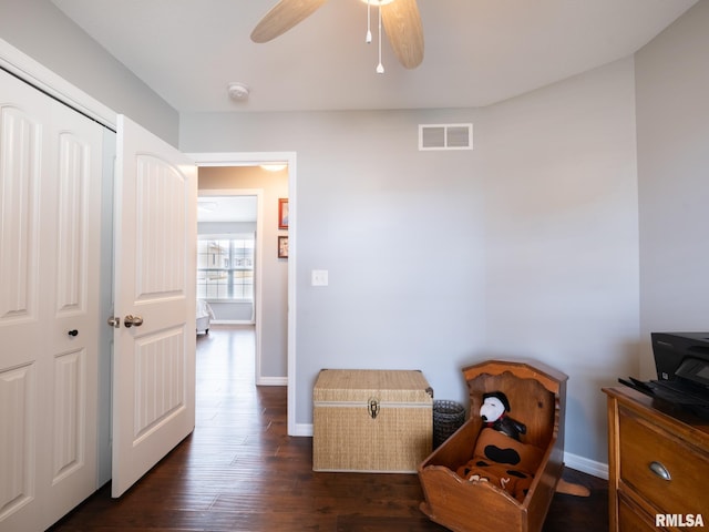 office area with dark wood-style floors, baseboards, visible vents, and a ceiling fan