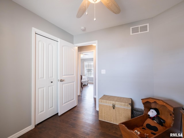 hallway featuring dark wood-style flooring, visible vents, and baseboards