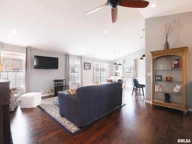 living area featuring a healthy amount of sunlight, vaulted ceiling, and dark wood-type flooring