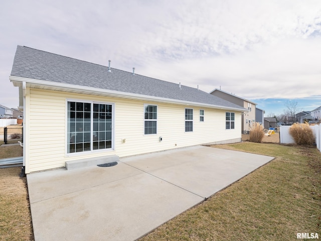 back of house with a shingled roof, fence, a lawn, and a patio