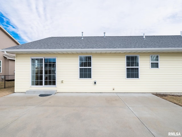 back of house with a shingled roof, a patio area, and fence