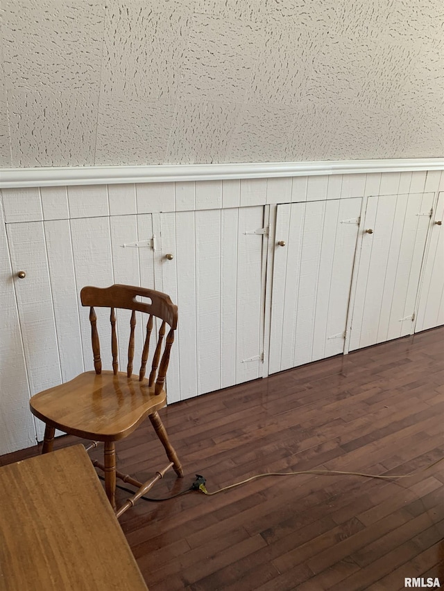 unfurnished room featuring wood-type flooring and a wainscoted wall