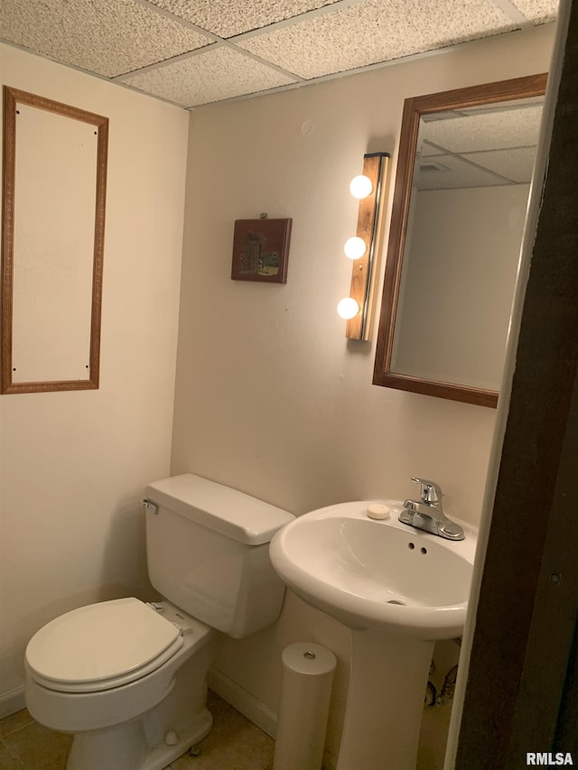 bathroom featuring a drop ceiling, toilet, and baseboards