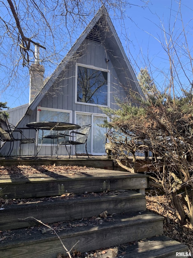 exterior space with board and batten siding and a chimney