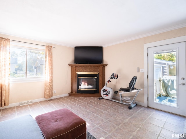 interior space with ornamental molding, a glass covered fireplace, visible vents, and baseboards