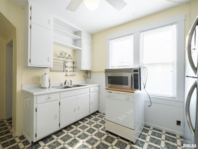 kitchen featuring light floors, open shelves, stainless steel microwave, white dishwasher, and a sink