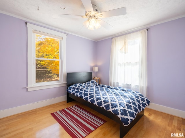 bedroom with ornamental molding, a textured ceiling, and wood finished floors