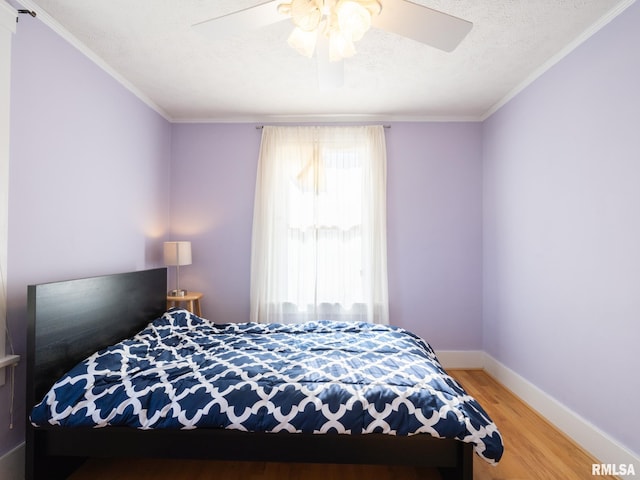 bedroom with crown molding, a textured ceiling, baseboards, and wood finished floors