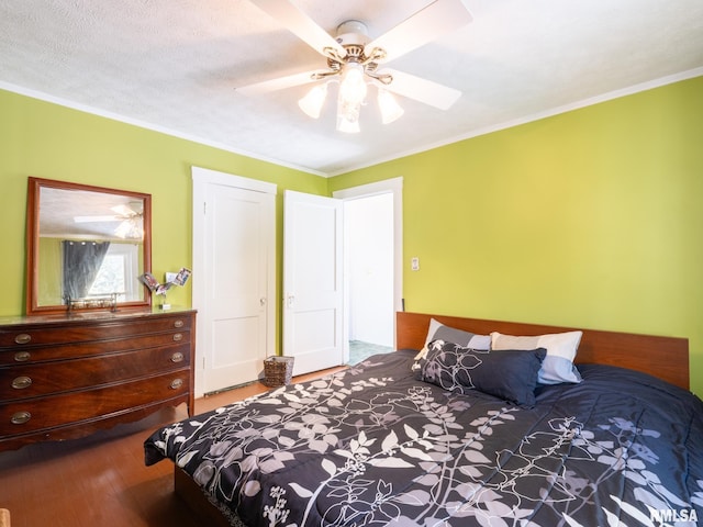 bedroom featuring ornamental molding, ceiling fan, a textured ceiling, and wood finished floors