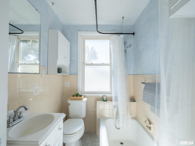 bathroom featuring a wainscoted wall, tile walls, shower / bathtub combination with curtain, toilet, and vanity