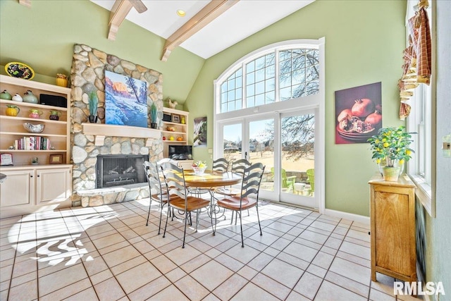 dining space featuring french doors, light tile patterned floors, a towering ceiling, a stone fireplace, and beamed ceiling