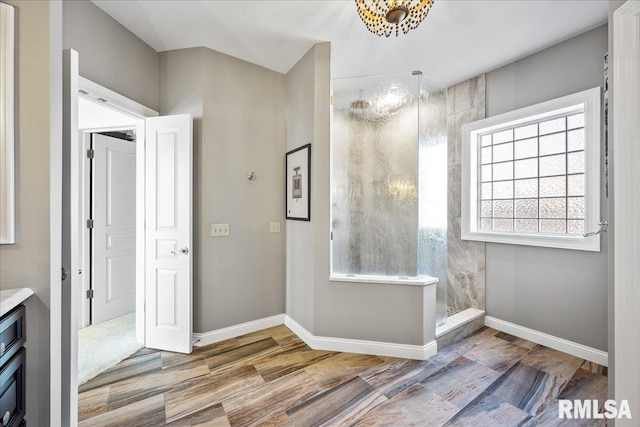 bathroom with baseboards, tiled shower, and wood finished floors