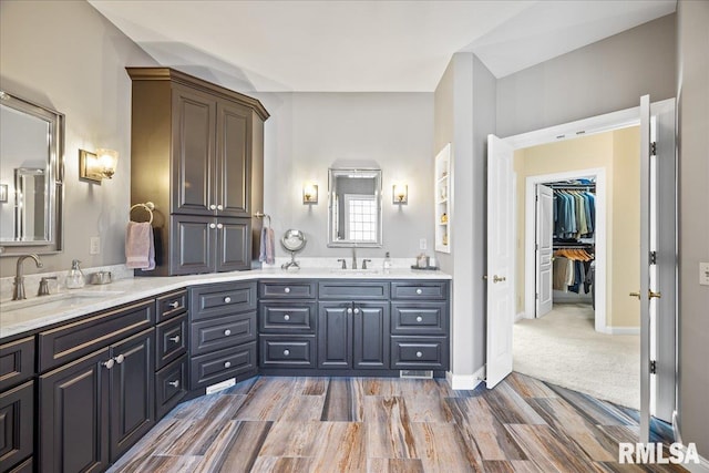 full bathroom with double vanity, a sink, and wood finished floors